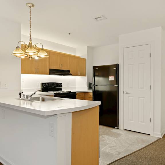 a kitchen with a white counter and a brown floor mat.