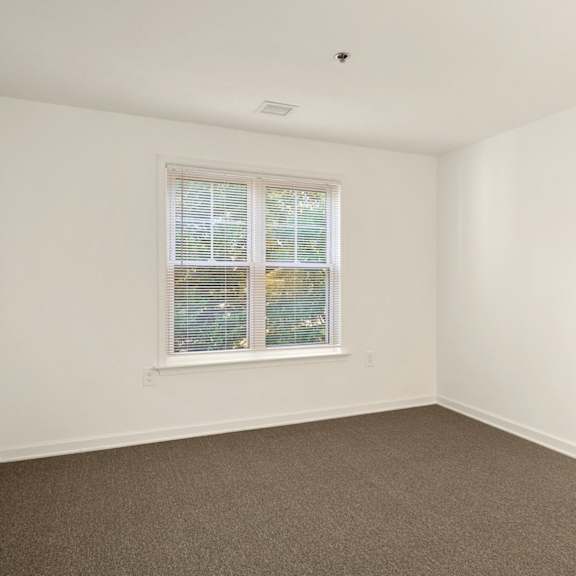 a room with a window and carpeted floor.
