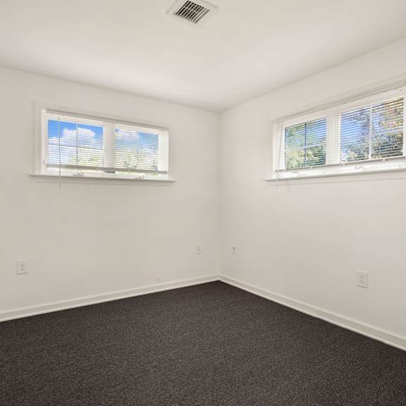 a room with two windows and carpeted floor.