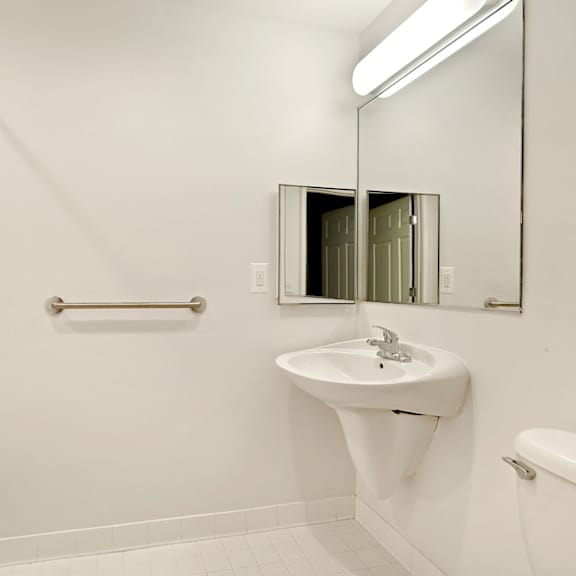 a white bathroom with a sink, mirror, and bathtub.