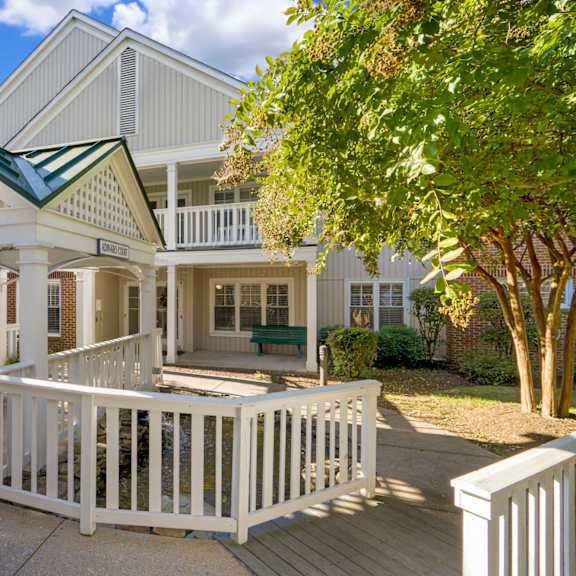 a white house with a green roof and a porch.