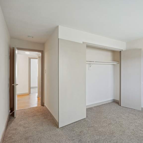 a white room with a carpeted floor and a closet with a sliding door.