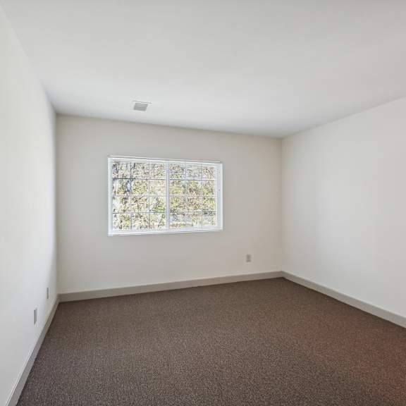 a room with a window and carpeted floor.