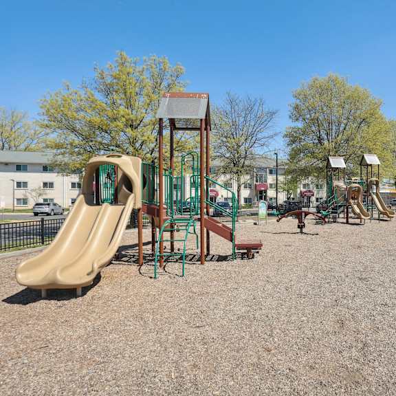 a playground with a slide, swings, and a seesaw.