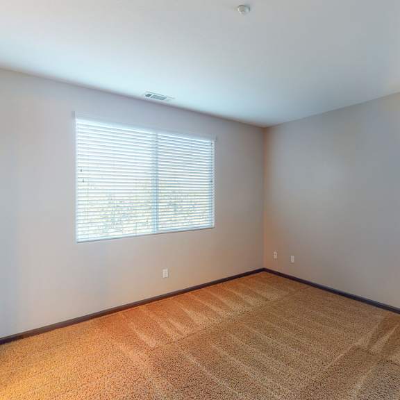 a room with a carpeted floor and two windows.