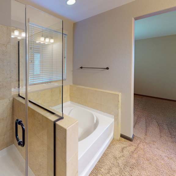 a bathroom with a tiled shower and a glass door.