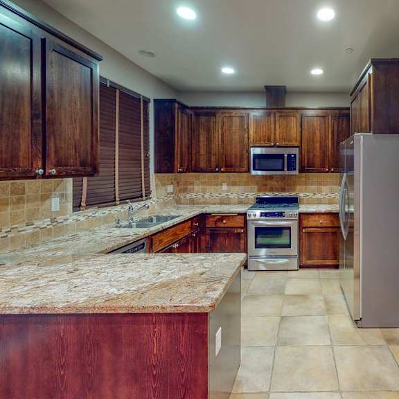 a kitchen with wooden cabinets and a marble countertop.