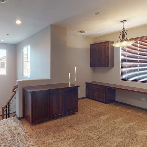 a room with a brown carpet and wooden furniture.