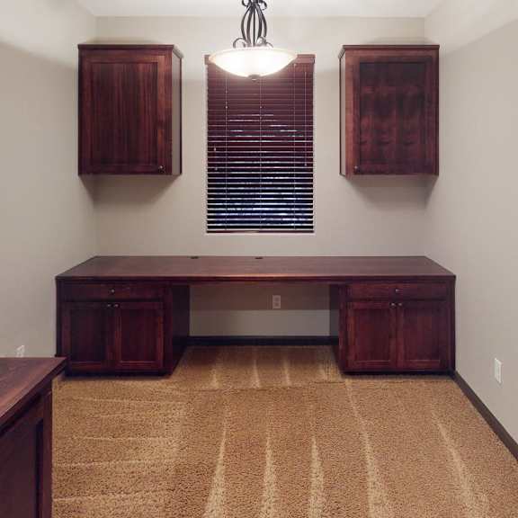 a room with a brown carpet and wooden furniture.