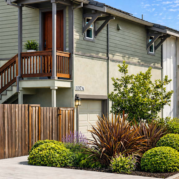 a grey house with a brown door and a balcony.