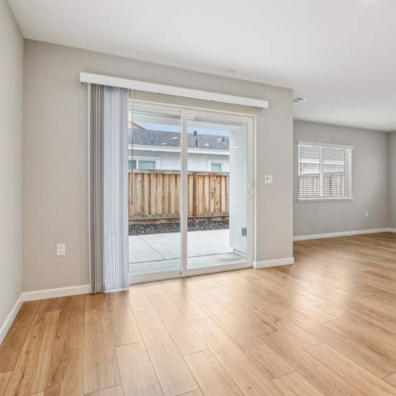 a room with wooden flooring and a sliding glass door leading outside.