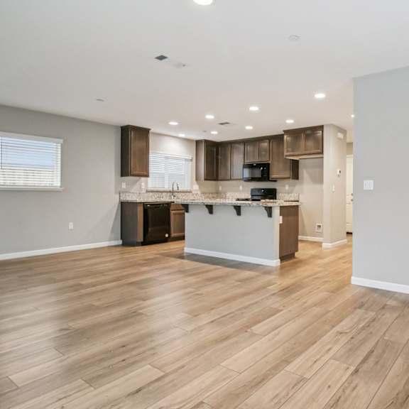 a spacious kitchen with wooden floors and white walls.