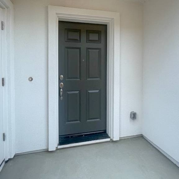 a dark grey door is in a white room.