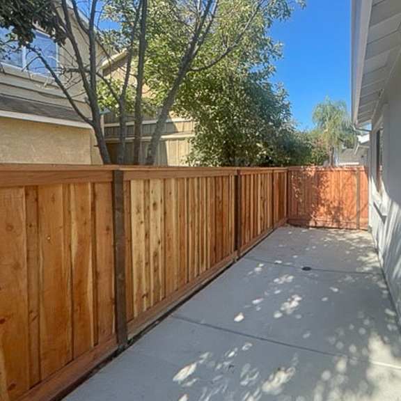 a wooden fence runs along the side of a house.