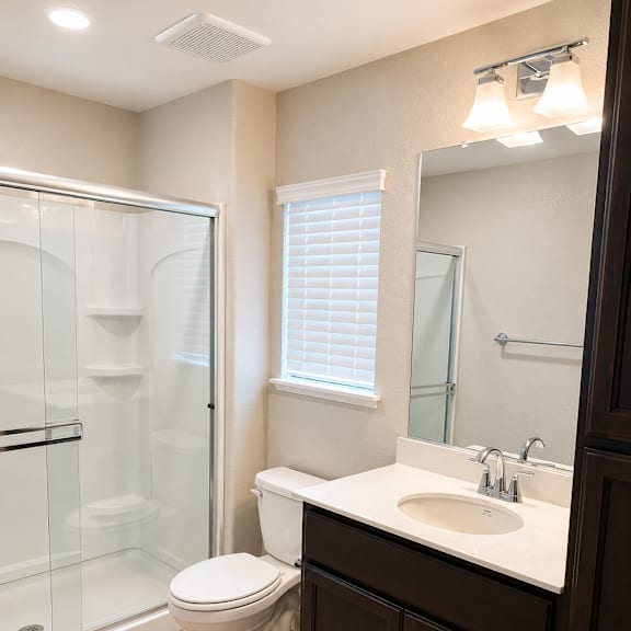 a bathroom with a toilet, sink, and shower.
