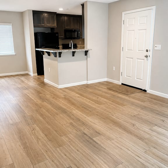 a kitchen with a white door and a wooden floor.
