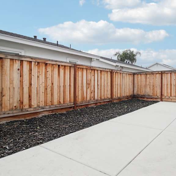 a backyard with a wooden fence and a white wall.