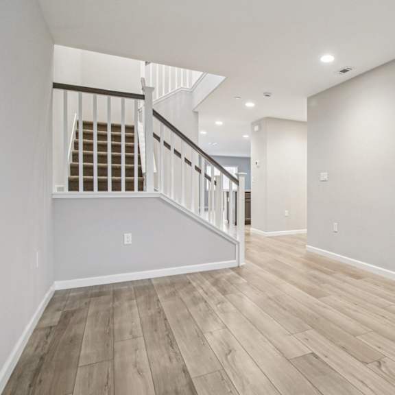 a room with a wooden floor and a staircase with a metal railing.