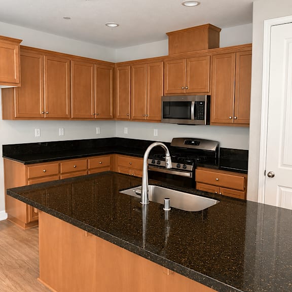a kitchen with wooden cabinets and a black granite countertop.