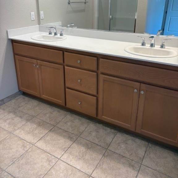 a bathroom with a white counter top and brown cabinets.