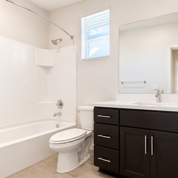 a white toilet sits in a bathroom with black cabinets.