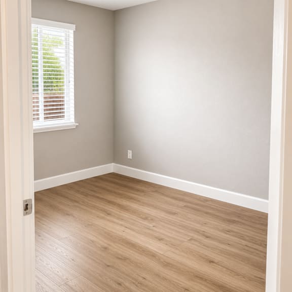 a room with a window and wooden flooring.