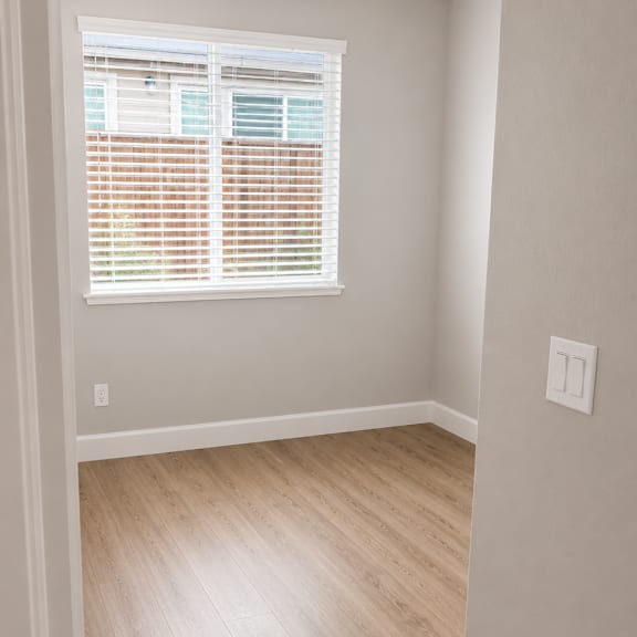 a room with a wooden floor and a window with blinds.