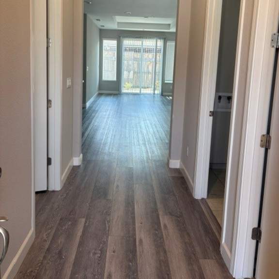 a long hallway with white walls and wood flooring.