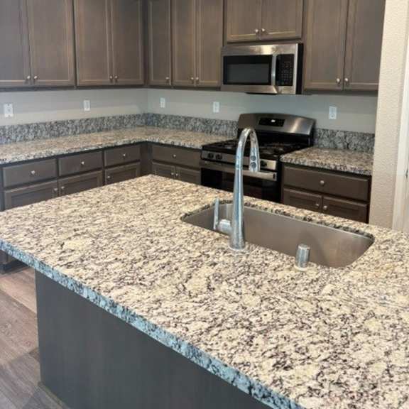 a kitchen with granite countertops and wooden cabinets.
