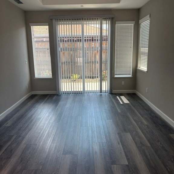 a room with a sliding glass door and dark wood flooring.