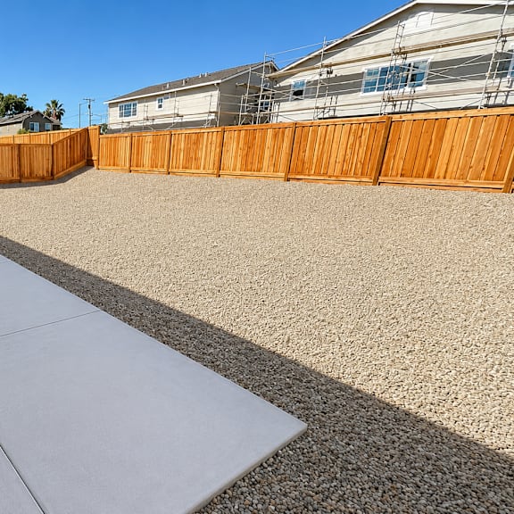 a backyard with a concrete patio and a wooden fence.