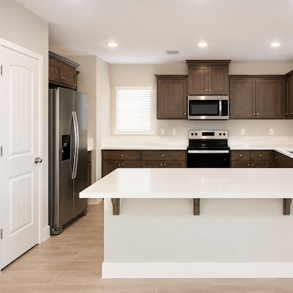 a kitchen with a white countertop and brown cabinets.