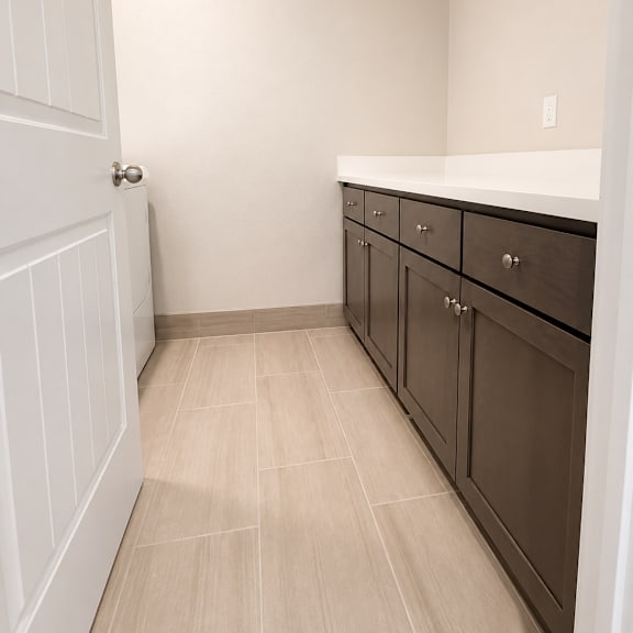 a white door is open to a hallway with brown cabinets.