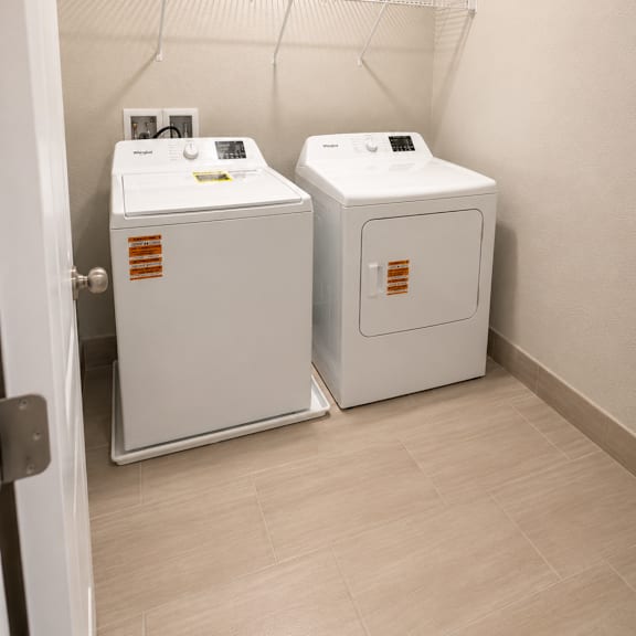 two white washing machines in a small laundry room.