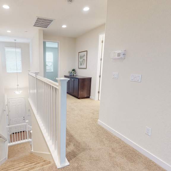 a white staircase with a railing leads to a second floor.