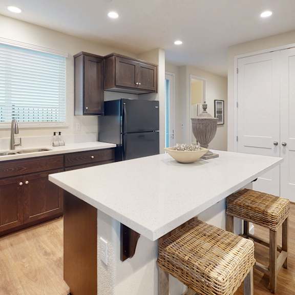a kitchen with a white table and brown chairs.