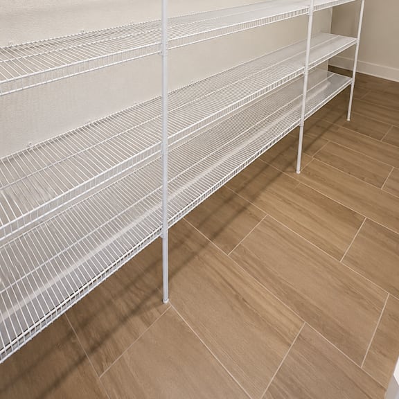 empty shelves in a room with light brown flooring.