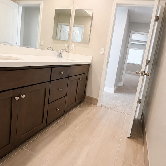 a bathroom with a sink, mirror, and wooden floors.