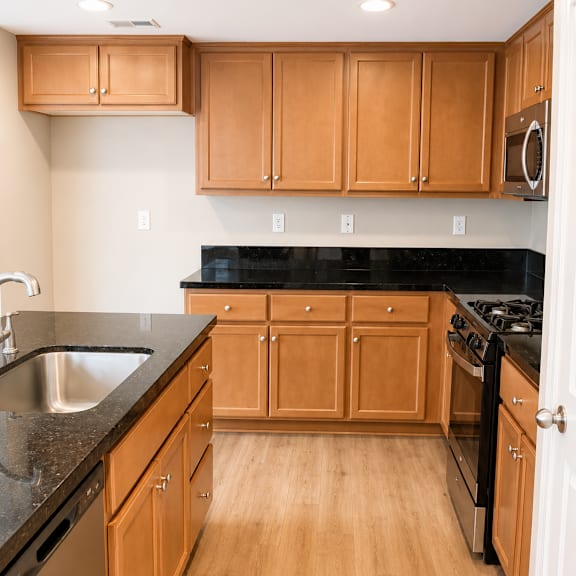 a kitchen with wooden cabinets and black countertops.