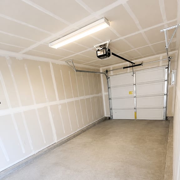 a garage with a white door and a white ceiling with a light on it.