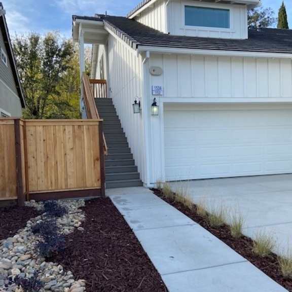 a white house with a garage and a wooden fence.