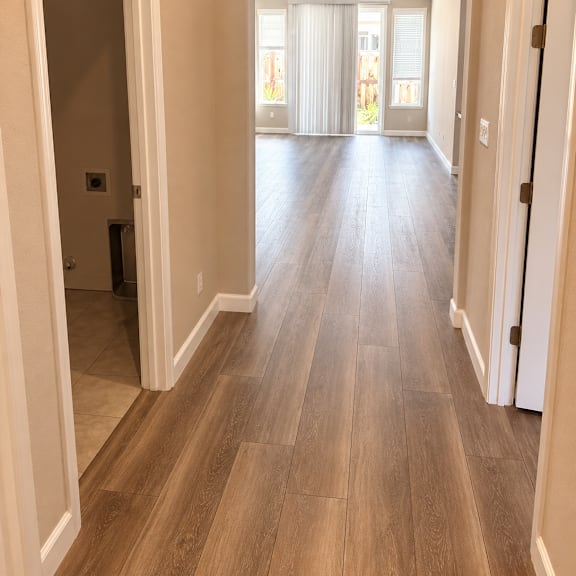 a long hallway with wood floors and white walls.