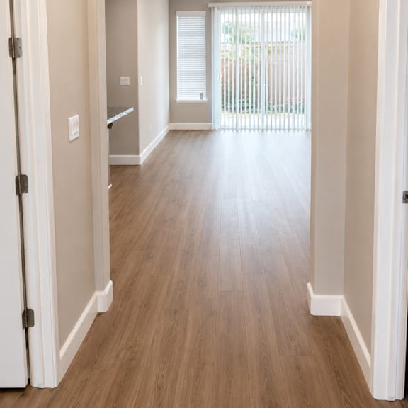 a long hallway with wood floors and white walls.