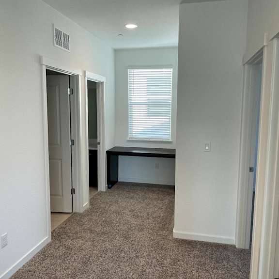 a white kitchen with a microwave and a window.