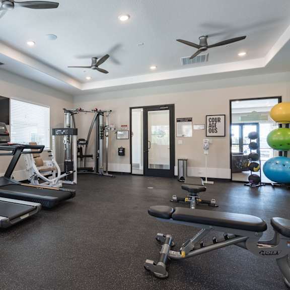 an exercise room with treadmills and weights and a tv at heritage landing apartments, chico, california