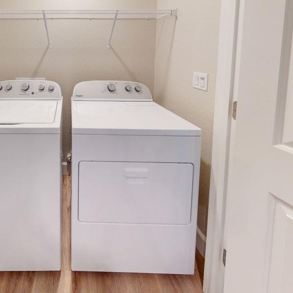 two washers and dryers in a laundry room with a door at heritage landing apartments, chico, california