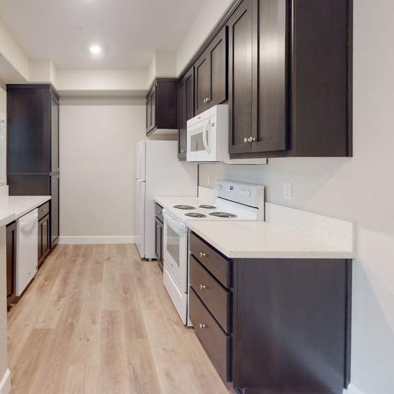 a kitchen with black cabinets and white counter tops and a wood floor at heritage landing apartments, chico, ca, 95973
