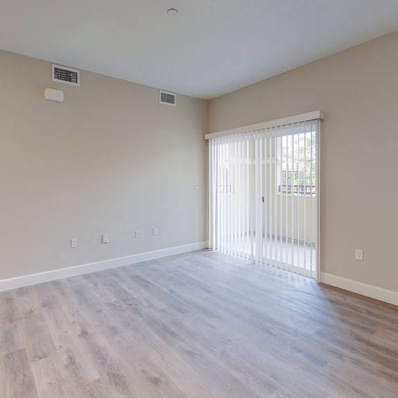 an empty living room with wood floors and a door to a balcony at heritage landing apartments, chico, ca
