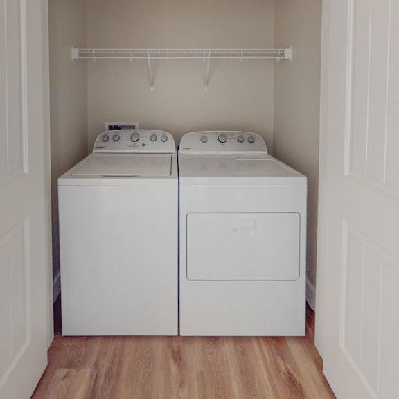 a washer and dryer in a laundry room with white walls and wood floors at heritage landing apartments, chico, ca, 95973