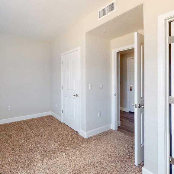 a bedroom with white walls and carpet and a door to a closet at heritage landing apartments, california